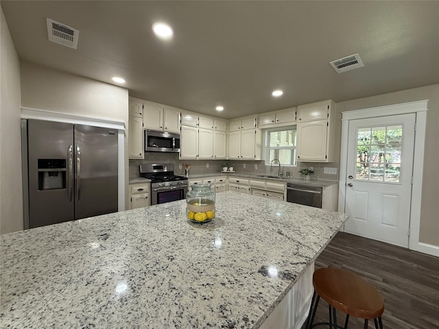 2849 Spruce Park Dr, Richland Hills, TX 76118 - kitchen featuring appliances with stainless steel finishes, dark wood-type flooring, white cabinets, light stone counters, and backsplash