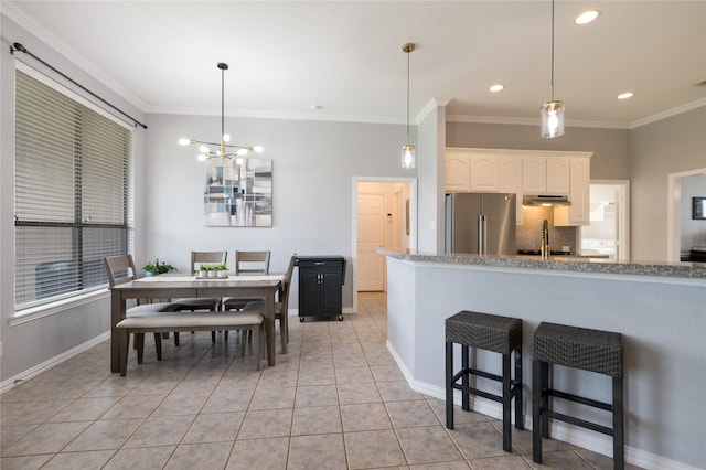3217 S Bay Breeze Ln, Fort Worth, TX 76179 - kitchen featuring freestanding refrigerator, ornamental molding, white cabinetry, light tile patterned flooring, and a kitchen breakfast bar