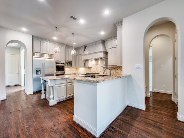 2911 Blackthorn Dr, Prosper, TX 75078 - kitchen featuring built in appliances, wall chimney exhaust hood, light stone countertops, decorative backsplash, and recessed lighting