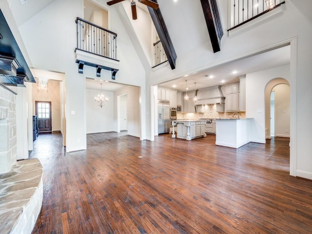 2911 Blackthorn Dr, Prosper, TX 75078 - unfurnished living room with high vaulted ceiling, ceiling fan, arched walkways, a chandelier, and dark wood finished floors