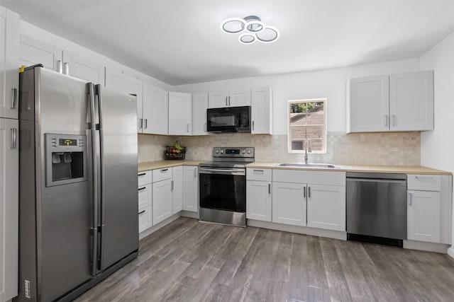 4236 Virginia Ln, Fort Worth, TX 76103 - kitchen featuring stainless steel appliances, light countertops, wood finished floors, and decorative backsplash