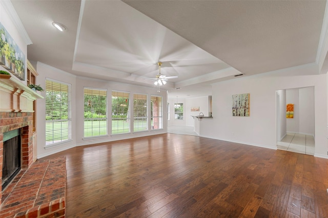 2403 Berry Grove Ct, Melissa, TX 75454 - unfurnished living room with a tray ceiling, a brick fireplace, ceiling fan, hardwood / wood-style floors, and ornamental molding