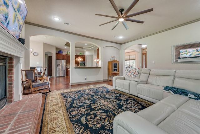 206 Hidden Meadow Cir, Midlothian, TX 76065 - living room featuring crown molding, arched walkways, ceiling fan, a brick fireplace, and wood finished floors