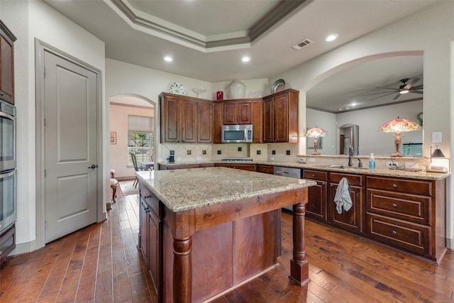 206 Hidden Meadow Cir, Midlothian, TX 76065 - kitchen featuring appliances with stainless steel finishes, arched walkways, ornamental molding, a ceiling fan, and dark wood-type flooring