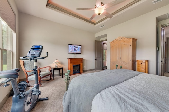 206 Hidden Meadow Cir, Midlothian, TX 76065 - bedroom with carpet flooring, a tray ceiling, a glass covered fireplace, and a ceiling fan
