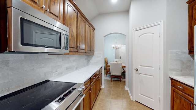 751 Kirby Dr, Argyle, TX 76226 - kitchen featuring appliances with stainless steel finishes, backsplash, arched walkways, light stone countertops, and light tile patterned floors
