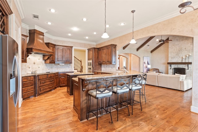 229 Lakeside Dr, Malakoff, TX 75148 - kitchen with appliances with stainless steel finishes, custom range hood, arched walkways, a ceiling fan, and a breakfast bar