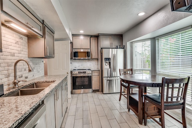 3412 Forest Creek Dr, Fort Worth, TX 76123 - kitchen with appliances with stainless steel finishes, decorative backsplash, light stone counters, recessed lighting, and light wood-style flooring