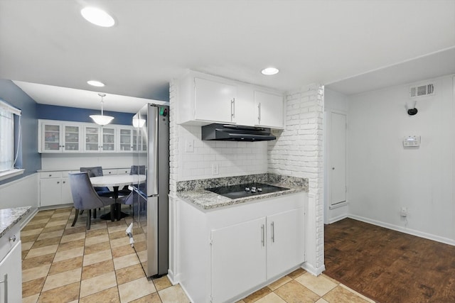 6123 Moonglow Dr, Dallas, TX 75241 - kitchen featuring black electric stovetop, freestanding refrigerator, under cabinet range hood, white cabinets, and tasteful backsplash