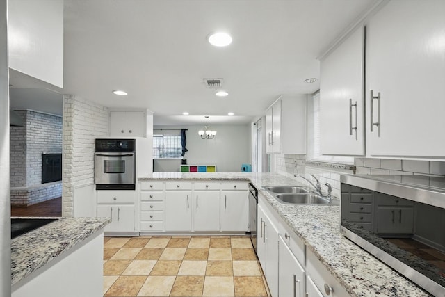 6123 Moonglow Dr, Dallas, TX 75241 - kitchen featuring stainless steel oven, white cabinets, a fireplace, backsplash, and recessed lighting