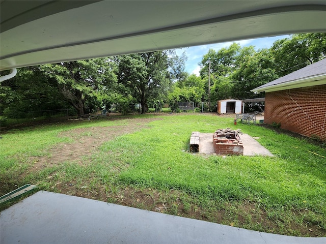 1721 Monaco Dr, Arlington, TX 76010 - view of yard featuring an outdoor fire pit, a storage unit, a patio, and view of wooded area