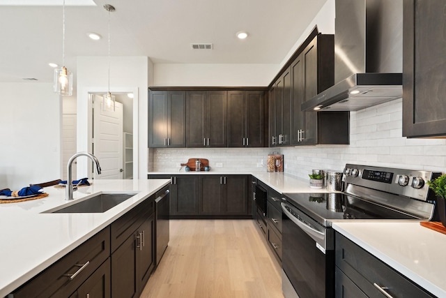 2105 Oak Haven Ct, Garland, TX 75044 - kitchen featuring stainless steel appliances, wall chimney exhaust hood, light countertops, light wood-style flooring, and tasteful backsplash
