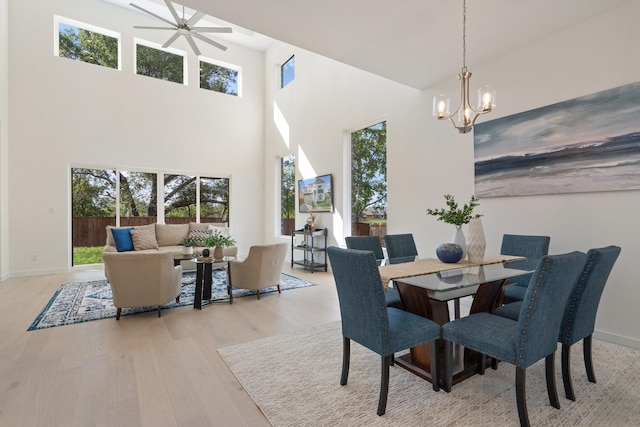 2105 Oak Haven Ct, Garland, TX 75044 - dining room featuring plenty of natural light, wood finished floors, a ceiling fan, a towering ceiling, and a chandelier