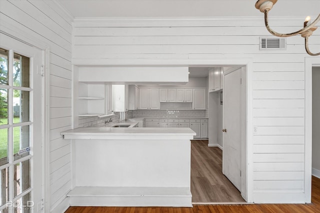 174 Carrollton Ave, Shreveport, LA 71105 - kitchen featuring a peninsula, backsplash, light countertops, wood walls, and ornamental molding