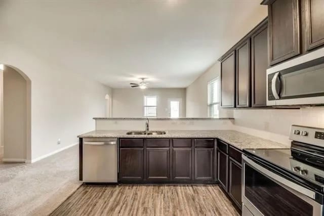 220 Aaron St, Anna, TX 75409 - kitchen featuring appliances with stainless steel finishes, ceiling fan, a peninsula, dark brown cabinetry, and arched walkways
