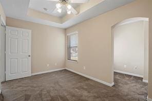 5729 Blackmon Ct, Fort Worth, TX 76137 - unfurnished bedroom with arched walkways, carpet flooring, and a raised ceiling