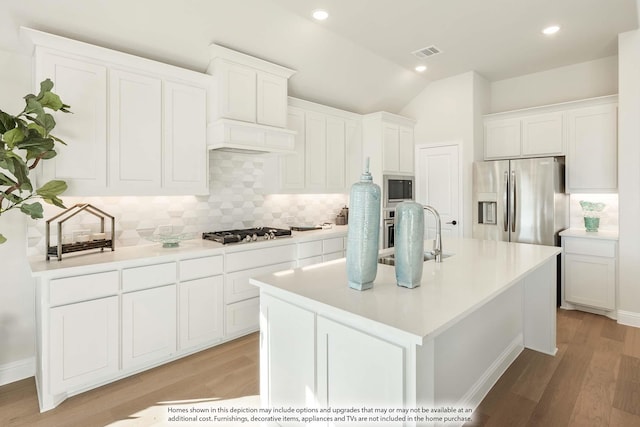 3803 Hidden Cove Ct, Rockwall, TX 75032 - kitchen featuring stainless steel appliances, tasteful backsplash, light wood-type flooring, white cabinetry, and vaulted ceiling
