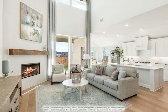 3803 Hidden Cove Ct, Rockwall, TX 75032 - living room featuring light wood-style flooring, a tile fireplace, and a high ceiling