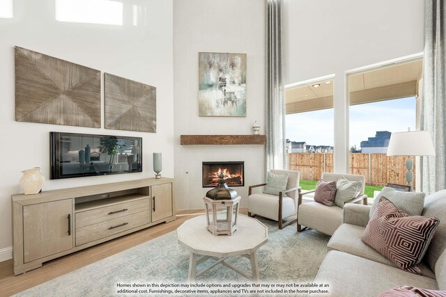 3803 Hidden Cove Ct, Rockwall, TX 75032 - living room with plenty of natural light, wood finished floors, a high ceiling, and a warm lit fireplace