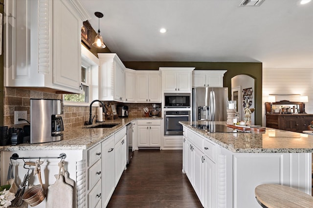 5885 State Highway 160, Whitewright, TX 75491 - kitchen with appliances with stainless steel finishes, white cabinetry, a kitchen island, light stone counters, and dark wood-style flooring