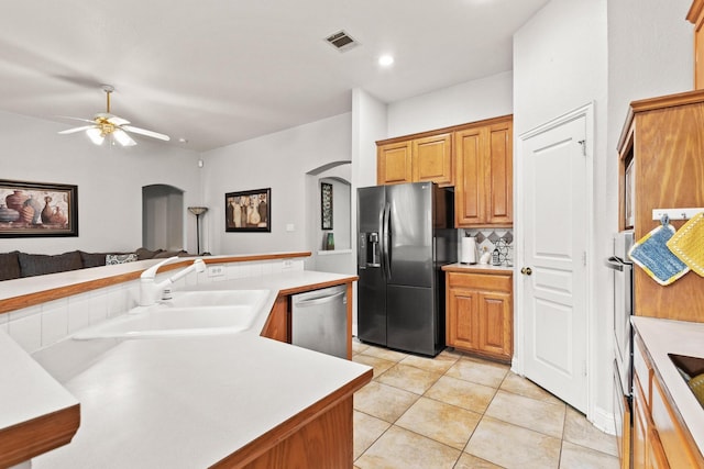 2009 Lake Fork Ct, Denton, TX 76210 - kitchen featuring appliances with stainless steel finishes, arched walkways, a ceiling fan, tasteful backsplash, and light tile patterned floors