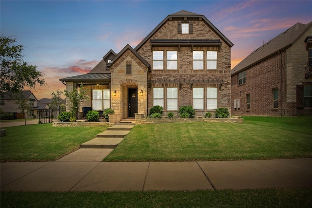 11504 Dawn Mist Dr, Frisco, TX 75035 - tudor-style house featuring a front yard, a standing seam roof, stone siding, and brick siding