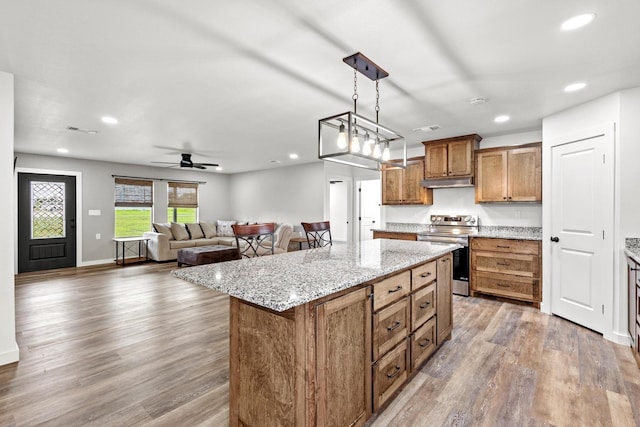293 Private Road 36008, Honey Grove, TX 75446 - kitchen featuring stainless steel range with electric cooktop, under cabinet range hood, wood finished floors, recessed lighting, and brown cabinets
