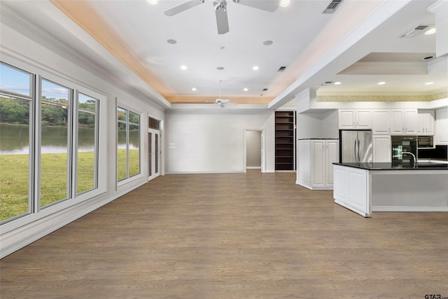 13735 Peninsula Rd, Whitehouse, TX 75791 - unfurnished living room featuring ceiling fan, a water view, wood finished floors, a raised ceiling, and recessed lighting