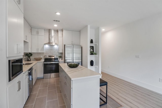154 S Cisco St, Dallas, TX 75246 - kitchen with stainless steel appliances, wall chimney exhaust hood, a center island, a kitchen bar, and decorative backsplash