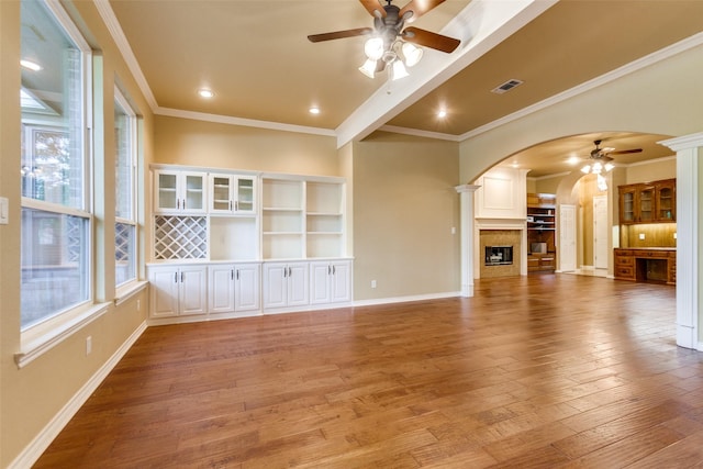 3506 Ash Cir, Richardson, TX 75082 - unfurnished living room featuring a ceiling fan, arched walkways, decorative columns, wood-type flooring, and ornamental molding