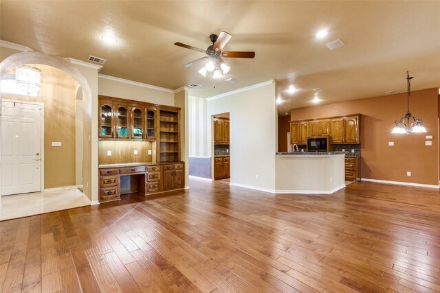 3506 Ash Cir, Richardson, TX 75082 - unfurnished living room with light wood-style floors, ceiling fan, ornamental molding, built in desk, and arched walkways