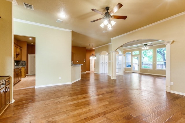 3506 Ash Cir, Richardson, TX 75082 - unfurnished living room featuring a ceiling fan, arched walkways, ornate columns, crown molding, and light wood-type flooring