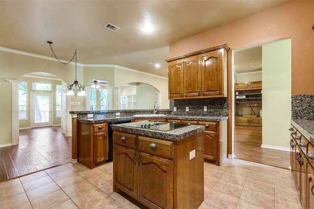 3506 Ash Cir, Richardson, TX 75082 - kitchen with arched walkways, black appliances, decorative columns, a kitchen island, and decorative backsplash