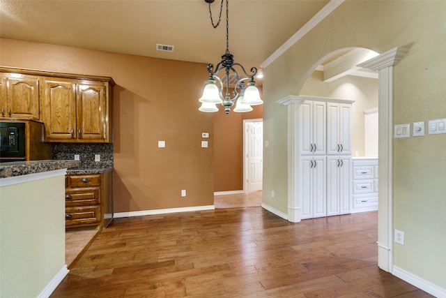 3506 Ash Cir, Richardson, TX 75082 - kitchen featuring hardwood / wood-style floors, a chandelier, brown cabinets, hanging light fixtures, and arched walkways