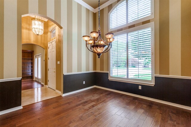 3506 Ash Cir, Richardson, TX 75082 - empty room featuring a chandelier, arched walkways, wood finished floors, ornamental molding, and a high ceiling