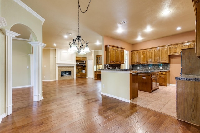 3506 Ash Cir, Richardson, TX 75082 - kitchen featuring brown cabinets, decorative backsplash, light wood finished floors, a chandelier, and ornamental molding