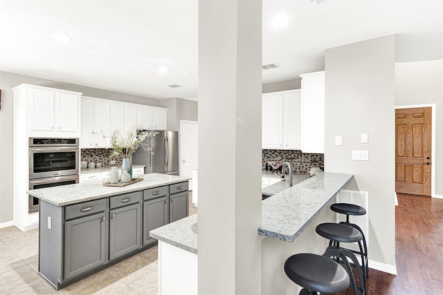4512 Greenfield Dr, Richardson, TX 75082 - kitchen featuring appliances with stainless steel finishes, gray cabinetry, backsplash, white cabinets, and recessed lighting