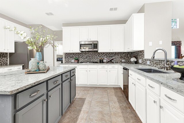 4512 Greenfield Dr, Richardson, TX 75082 - kitchen featuring gray cabinetry, appliances with stainless steel finishes, backsplash, white cabinets, and light stone counters