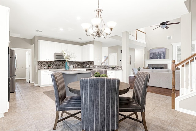 4512 Greenfield Dr, Richardson, TX 75082 - dining room featuring stairs, a ceiling fan, a chandelier, a tile fireplace, and light tile patterned floors