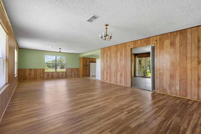 1210 E Fm 902, Howe, TX 75459 - unfurnished room with wood finished floors, wood walls, a chandelier, a textured ceiling, and a wainscoted wall