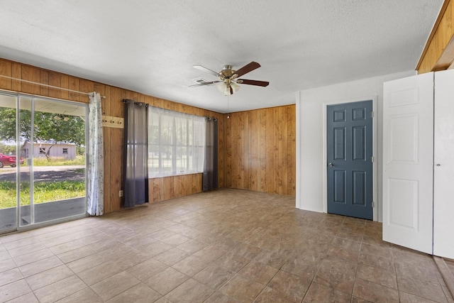 1206 Fm 902, Howe, TX 75090 - spare room with wood walls, a ceiling fan, and a textured ceiling