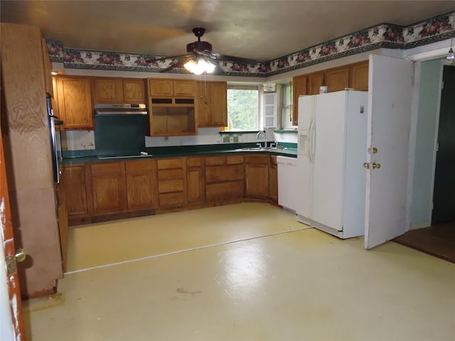 9066 Orinoco Dr, Dallas, TX 75217 - kitchen with white appliances, brown cabinetry, under cabinet range hood, ceiling fan, and dark countertops