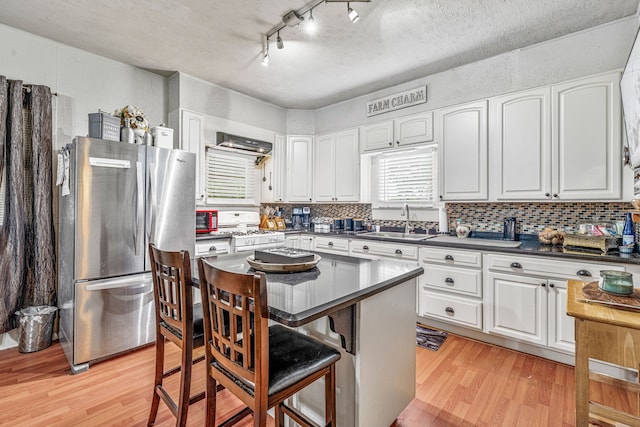 509 W Reynosa Ave, De Leon, TX 76444 - kitchen featuring freestanding refrigerator, white range with gas stovetop, light wood finished floors, and a breakfast bar area