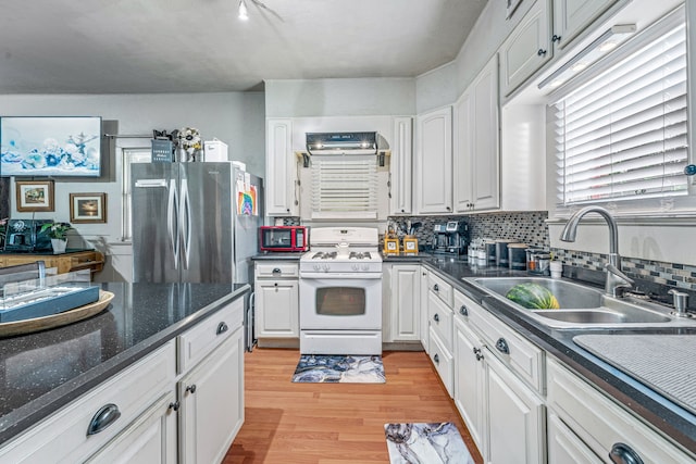 509 W Reynosa Ave, De Leon, TX 76444 - kitchen with white range with gas stovetop, freestanding refrigerator, light wood-style floors, and white cabinetry