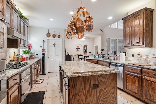 4105 Claridge Ter, Garland, TX 75043 - kitchen featuring appliances with stainless steel finishes, a center island, light tile patterned floors, light stone counters, and recessed lighting