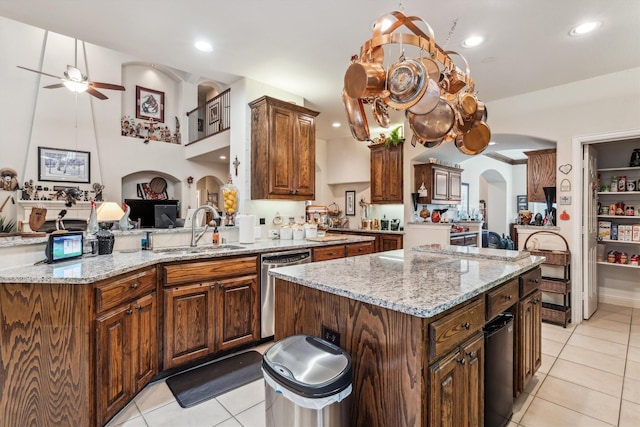 4105 Claridge Ter, Garland, TX 75043 - kitchen featuring arched walkways, stainless steel dishwasher, a ceiling fan, light tile patterned floors, and a center island