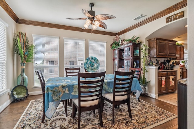 4105 Claridge Ter, Garland, TX 75043 - dining area featuring a ceiling fan, light wood finished floors, ornamental molding, and arched walkways