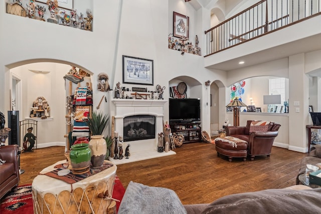 4105 Claridge Ter, Garland, TX 75043 - living room featuring a towering ceiling, wood finished floors, arched walkways, and a fireplace with raised hearth