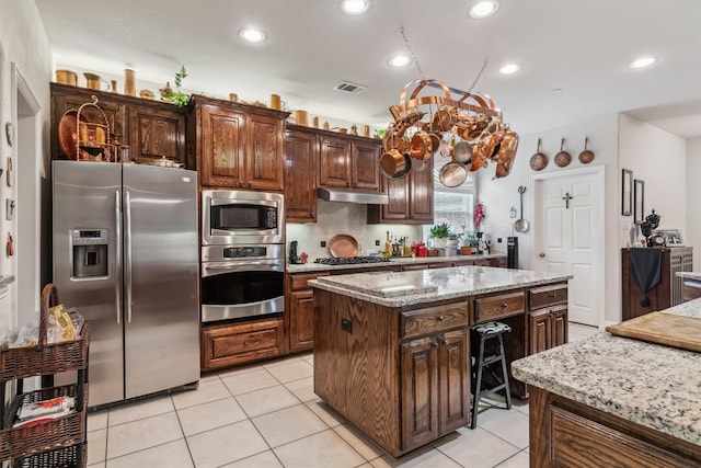 4105 Claridge Ter, Garland, TX 75043 - kitchen with appliances with stainless steel finishes, under cabinet range hood, a center island, recessed lighting, and light tile patterned flooring