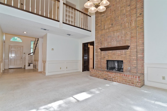 748 Arbor Creek Dr, Desoto, TX 75115 - unfurnished living room with a towering ceiling, a decorative wall, carpet floors, a brick fireplace, and a chandelier